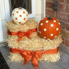 two pumpkins are sitting on hay bales in front of a door with an orange bow