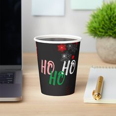 a coffee cup sitting on top of a wooden table next to a laptop and pen