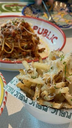 two bowls filled with food on top of a table next to another bowl full of pasta