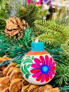 a colorful ornament sitting on top of pine cones