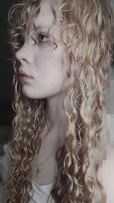 a woman with long curly hair is looking off to the side