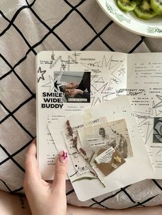 a person's hand on top of an open book with pictures and kiwis