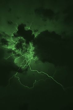 a green and black sky with lightning striking through the clouds in the distance, taken at night time