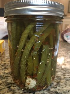 pickled green beans sit in a jar on the counter top, ready to be cooked