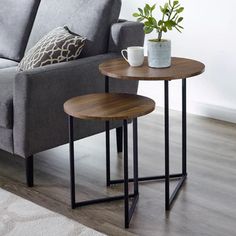 two tables sitting on top of a wooden floor next to a gray couch in a living room