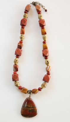 A red creek Jasper necklace with hexagon wooden beads, brass beads from Ghana and carnelian spacer beads and is 24 inches long, 27 inched long with a large triangle piece of red creek Jasper pendant.  This can be worn year round, dressed up or down. an extender chain has been added to shorten or lengthen it.  A free pair of matching earrings is included in the price of $90. Red Creek Jasper, Brass Beads, Jasper Necklace, Brass Necklace, Jasper Pendant, Spacer Beads, Wooden Beads, Chain Styles, Matching Earrings