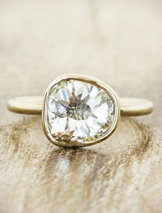 a close up of a ring with a diamond on the top and bottom, sitting on a wooden surface