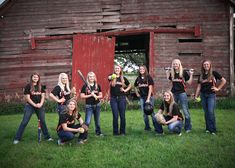 a group of young women standing next to each other in front of a barn