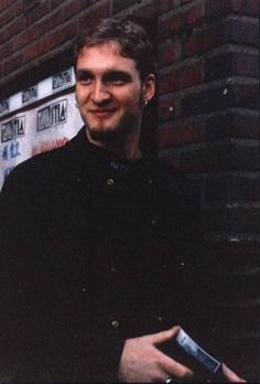 a man standing in front of a brick wall