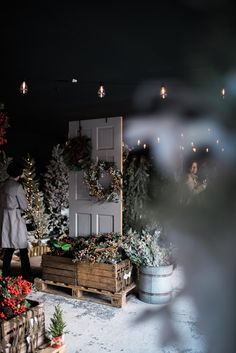 a man standing in front of a display of christmas trees and wreaths at night