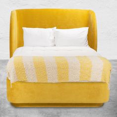 a large yellow bed with white pillows and blankets on it's headboard, in front of a white background