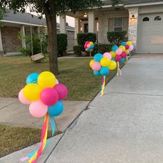 balloons are lined up on the sidewalk in front of a house