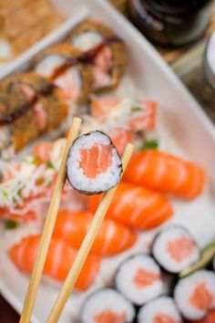 sushi and chopsticks on a plate with other food items in the background