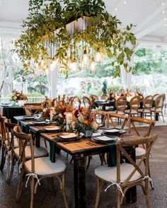 a dining room with tables and chairs covered in greenery