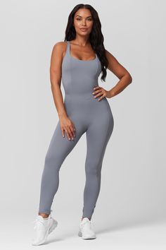 The Lace Up Legging Jumpsuit is designed to flatter your figure. Its lace up back ensures a custom fit while its square neckline adds an elegant touch. Its improved fabric provides medium compression for comfort and curve accentuating stitching detail adds to the style. Get ready to look and feel fabulous in this jumpsuit! The Details: Lace up back Square neck Form-fitting No front seam Built-in shelf bra with removable cups 87% Polyester/ 13% spandex Fitted Athleisure Jumpsuits And Rompers In Solid Color, Fitted Sports Bodysuit With Solid Back, Fitted Sleeveless Unitard For Loungewear, Fitted Gray Bodysuit For The Gym, Fitted Gray Bodysuit For Gym, Fitted Gray Bodysuit For Yoga, Fitted Jumpsuit With Built-in Bra For Gym, Sporty Fitted Gray Jumpsuits And Rompers, Solid Moisture-wicking Jumpsuit For Gym