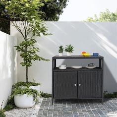 an outdoor table and planter in the middle of a patio with a white fence behind it