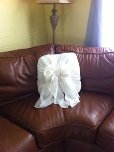 a brown leather couch with a white pillow on it and a lamp in the corner