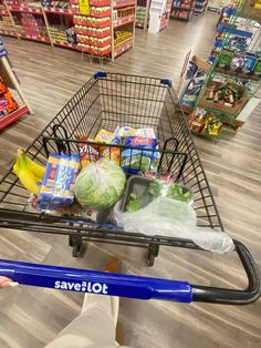 a person pushing a shopping cart in a store filled with groceries and food items on the floor