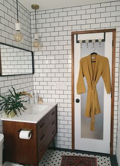 a white tiled bathroom with a wooden cabinet and sink