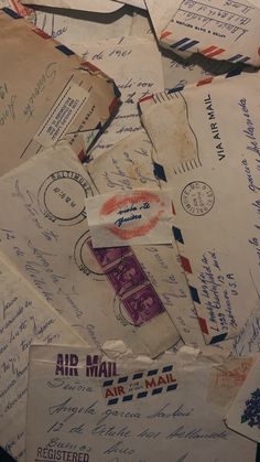 many mail envelopes are piled on top of each other with letters and postal stamps