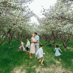 a group of people that are standing in the grass with some flowers on them and trees