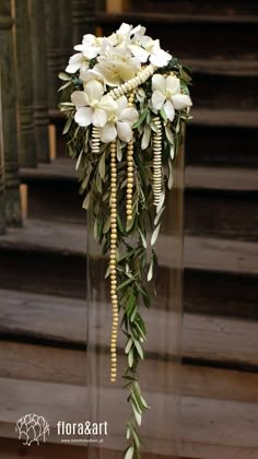 white flowers and greenery in a clear vase on the steps to an old building