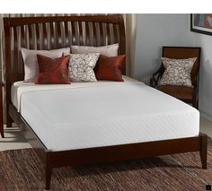 a bed with white sheets and brown headboard in a living room next to a window