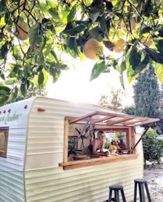 an old camper converted into a mobile home is parked under a tree with lemons hanging from the branches