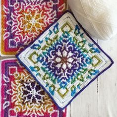 two crocheted square coasters sitting next to a ball of yarn