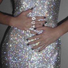 a woman with her hands on her hips wearing glitter dress and black nails, holding onto her hand