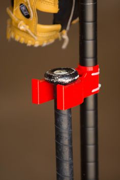 a baseball glove hanging from the back of a black and red pole with a yellow catcher's mitt on it