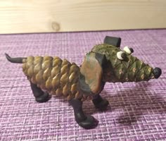 a toy dog made out of pine cones on top of a purple tableclothed surface