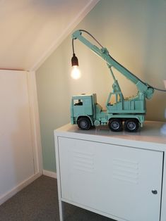 a toy crane is sitting on top of a dresser in the corner of a room