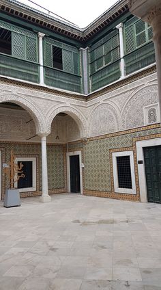 an empty courtyard with columns and doors in the center, surrounded by ornate tilework