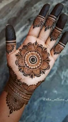 a hand with henna tattoos on it and an intricate design in the middle of it