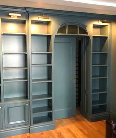 an empty room with blue bookcases and wooden floors