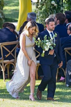 a bride and groom walking down the aisle at their outdoor wedding ceremony with guests in the background