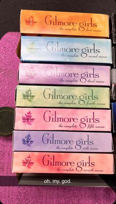 six books are stacked on top of each other in front of a purple cloth with the words, glimore girls