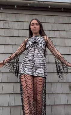 a woman wearing fishnet stockings standing in front of a building with her arms outstretched