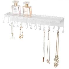 a white shelf with several necklaces and perfume bottles hanging from it's sides