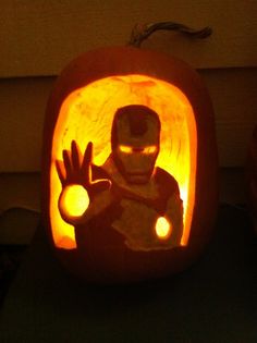 a pumpkin carved to look like iron man with glowing eyes and hands in front of it