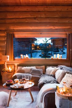 a living room filled with lots of furniture next to a large window covered in candles