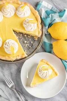 a lemon pie on a plate next to two lemons