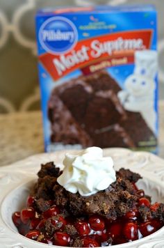 a white plate topped with brownies and cherries next to a box of frosting