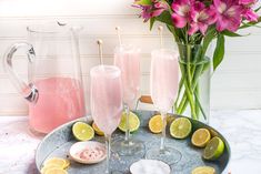 pink lemonade and limeade cocktails on a tray with flowers in the background