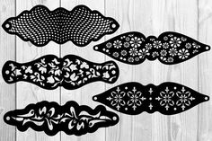 four black and white cut outs with flowers on them, sitting on top of a wooden surface