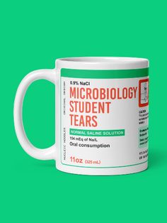 a white coffee mug with the words microbiology and tears on it against a green background