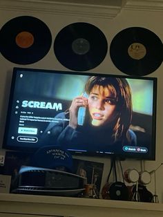 a flat screen tv mounted to the side of a wall next to record players and records