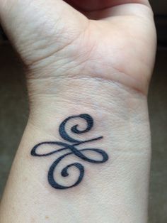 a small wrist tattoo with the letter g on it