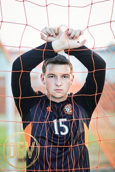 a young man standing in front of a soccer net with his hands on his head